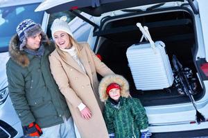 junge Familie während der Winterreise Kofferraum im Hintergrund foto