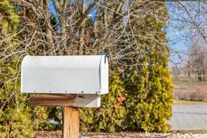 weißer Briefkasten oder Briefkasten. schöner alter Briefkasten auf Naturständer, Büsche drumherum. eiserner Briefkasten foto