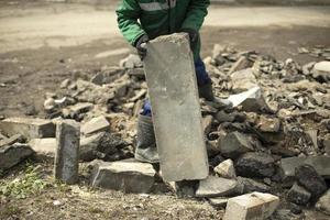 Arbeiter nimmt gebrochenen Stein. Reinigung von Bauschutt. foto