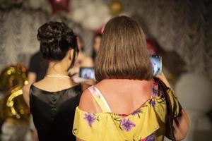 Personen an einem Feiertag in einer öffentlichen Einrichtung. zwei Mädchen, eines mit dunklen Haaren und einem schwarzen Kleid, das zweite mit blonden Haaren, einem gelben Kleid in einer Blume. foto