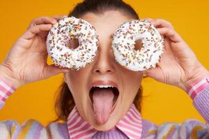 junge schöne Frau auf gelbem Hintergrund mit Donuts foto