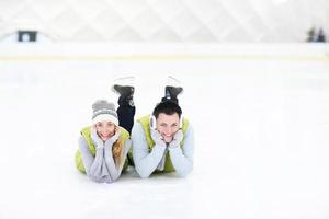 fröhliches paar, das auf der eisbahn liegt foto