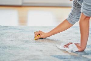 Bild einer Hand mit einem Schwamm, der den Teppich reinigt foto