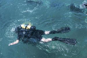 Draufsicht des Tauchers, der unter Wasser schwimmt und den Meeresboden untersucht. Taucherblasen, die von unten an die Oberfläche kommen. foto