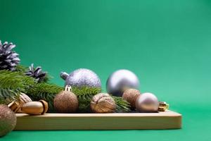 Silber- und Goldkugeln, Walnuss, Eichel mit Fichtenzweigen auf Sockel auf grünem Hintergrund. weihnachten, neujahr. Platz kopieren foto