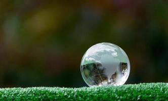 Nahaufnahme der Kristallkugel, die auf Gras in einem Wald ruht - Umweltkonzept foto