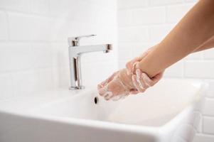 Frau wäscht sich zu Hause im Badezimmer die Hände foto