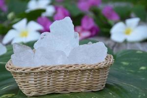 weicher Fokus von Alaunwürfeln und Plumeria-Blume auf kleinem Weidenkorb, verschwommener Hintergrund, Konzept für Kräuter, Körperpflege, Hautpflege, Wasserreinigung, Spa, Behandlung, Krankheitsschutz und Schutz der Achselgeruch. foto