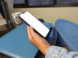 nahaufnahme einer frauenhand, die einen weißen smartphonebildschirm hält, ist leer. mockup. foto
