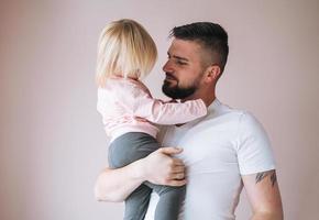 junger vater mit kleinem mädchen an den händen zu hause foto