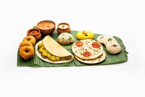 südindisches masala dosa, uttapam, idli vada sambar, grieß halwa, upma serviert auf bananenblatt foto