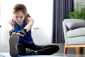 asiatische frauen wärmen sich auf, bevor sie zu hause trainieren. Training von zu Hause aus. foto
