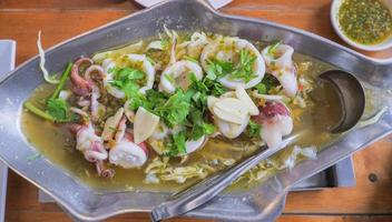 Gedünsteter Tintenfisch mit Limetten-Thai-Speise, in einem rostfreien heißen Topf in Fischform. foto