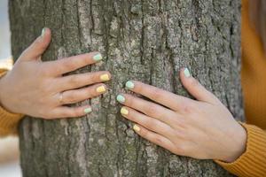 Die Hände der Frau umarmen die Rinde eines Baumes. foto