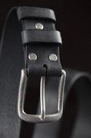 schwarzer Ledergürtel auf dunklem Hintergrund. Leder Produkte. foto
