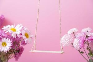 eine Schaukel mit Chrysanthemenblüten als Ständer für Ihr Kosmetikprodukt. kreatives Podium oder Podest foto