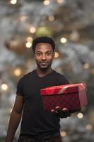 weihnachtsgeschenk mann zeigt überraschung, die geschenkbox feiertagsfeier auf beleuchtetem bokeh tannenbaum gibt foto