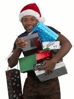 Mann, der Weihnachtsmann-Hut trägt und viele Weihnachtsgeschenkboxen hält, die auf weißem Hintergrund lokalisiert werden foto