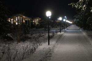 Weihnachtsstimmung. Landstraße und Hütten beleuchtet und dekoriert in der Dunkelheit, umgeben von Schneeverwehungen. ich foto
