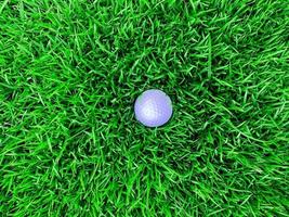 golfball nah oben auf grünem gras auf unscharfer schöner landschaft des golfplatzes mit sonnenaufgang, sonnenuntergangszeit auf hintergrund.konzept internationaler sport, der auf präzisionsfähigkeiten zur gesundheitsentspannung angewiesen ist. foto