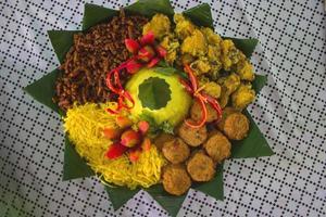 Nasi Kuning oder gelber Reis oder Kurkuma-Reis ist ein traditionelles Essen aus Asien, zubereiteter Reis, gekocht mit Kurkuma, Kokosmilch und Gewürzen, serviert mit Ei, Hühnchen, Erdnüssen, Chilisauce, foto