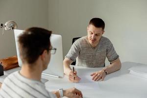 seriöser professioneller mann, der kunden im büro berät. zwei männer treffen sich, führen geschäftsgespräche. versicherer berät, manager macht angebot. Mentor Lehrpraktikant Vorstellungsgespräch. foto