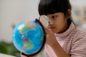 Asiatisches kleines Mädchen lernt das Globusmodell, das Konzept, die Welt zu retten und durch Spielaktivitäten für die Kindererziehung zu Hause zu lernen. foto