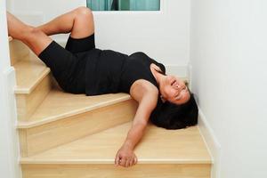 asiatische dame frau verletzung durch herunterfallen auf rutschigen oberflächen treppen zu hause. foto
