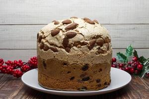 traditioneller Weihnachtspanettone. berühmtes italienisches dessert mit weihnachtsschmuck isoliert auf hölzernem hintergrund foto