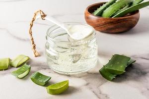 Vorderansicht eines Glasgefäßes mit einem Kosmetikprodukt auf Basis von Aloe-Extrakt und Blattscheiben. Naturkosmetik. nährt und befeuchtet die Haut. foto