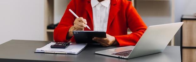 Geschäftsfrau arbeitet mit Laptop-Computer, Tablet und Smartphone im modernen Büro mit virtuellem Symboldiagramm im Modernoffice im Morgenlicht foto