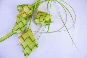 Ketupat in Tonplatte isoliert auf weißem Hintergrund. ketupat reisknödel ist ein essen, das in indonesien bei idhul fitri eid mubarak serviert wird und aus reis hergestellt wird, der in junge kokosnussblätter gewickelt ist, janur foto