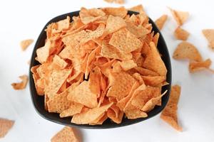 Tortilla-Chip ist Maischips oder nennt sich Nachos, serviert in einer Schüssel, auf schwarzem Hintergrund aus Mais foto