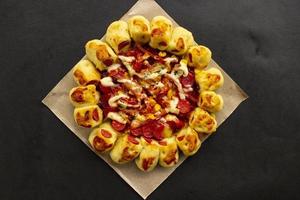 Köstliche Pizza serviert mit Pilzbelag, Mais, Hühnerwurst, Speck, Mayonnaise, Barbecue-Sauce, Tomate, Chili auf schwarzem Hintergrund. foto