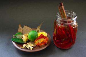 Wedang Uwuh ist ein traditionelles Kräutergetränk aus Indonesien. aus Zimt, Muskatnuss und Nelkenblättern. eine weitere zutat ist holz vom secangbaum, ingwer und würfelzucker auf schwarzem hintergrund foto