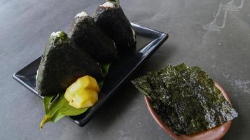 onigiri ist japanisches essen, japanischer reisball, reisdreieck mit algen, nori isoliert auf hintergrund foto