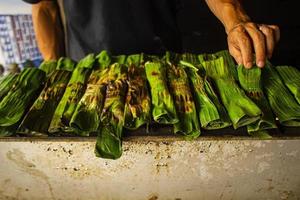 Otak - Otak ist ein Gericht aus gehacktem Makrelenfischfleisch, das in Bananenblätter gewickelt, gebacken und mit scharfer und saurer Soße serviert wird. Otak-Otak ist ein traditioneller Fischkuchen aus Indonesien foto