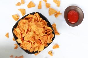 Tortilla-Chip ist Maischips oder nennt sich Nachos, serviert in einer Schüssel, auf schwarzem Hintergrund aus Mais foto