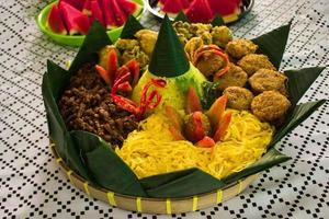 Nasi Kuning oder gelber Reis oder Kurkuma-Reis ist ein traditionelles Essen aus Asien, zubereiteter Reis, gekocht mit Kurkuma, Kokosmilch und Gewürzen, serviert mit Ei, Hühnchen, Erdnüssen, Chilisauce, foto