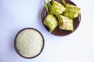 Ketupat in Tonplatte isoliert auf weißem Hintergrund. ketupat , Reisknödel ist ein Essen, das in Indonesien serviert wird, wenn Idhul Fitri Eid Mubarak aus Reis hergestellt wird, der in junge Kokosnussblätter gewickelt ist, Janur foto