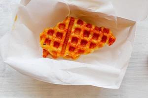 Croissant-Waffel oder Croffle mit Schokoladensauce, serviert in Schachtel und weißem Hintergrund foto