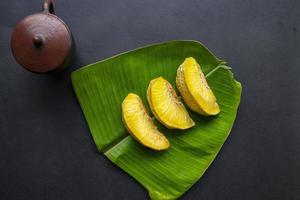 sukun goreng oder frittierte brotfrucht serviert auf bananenblatt auf schwarzem hintergrund foto