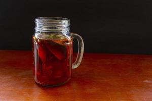 Wedang Uwuh ist ein traditionelles Kräutergetränk aus Indonesien. aus Zimt, Muskatnuss und Nelkenblättern. eine weitere zutat ist holz vom secangbaum, ingwer und würfelzucker auf schwarzem hintergrund foto