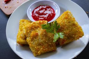 frittierte risole oder risol mayo sind indonesische snacks. wie coxinha de galinha. serviert mit Chilisauce, Sellerie auf Holzplatte foto