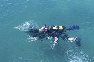 Draufsicht des Tauchers, der unter Wasser schwimmt und den Meeresboden untersucht. Taucherblasen, die von unten an die Oberfläche kommen. foto