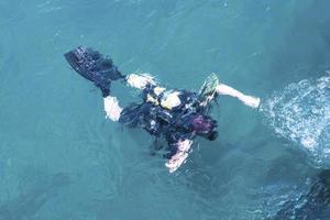 Draufsicht des Tauchers, der unter Wasser schwimmt und den Meeresboden untersucht. Taucherblasen, die von unten an die Oberfläche kommen. foto