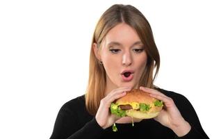 Porträt eines schönen lustigen jungen Mädchens, das Hamburger isst foto