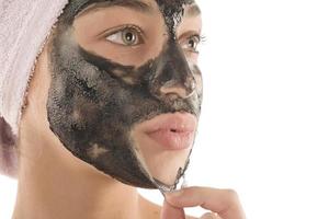 schwarze Gesichtsmaske. schönes Mädchen, das schwarze Maske ablegt. Beauty-Konzept foto