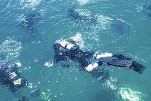 Draufsicht des Tauchers, der unter Wasser schwimmt und den Meeresboden untersucht. Taucherblasen, die von unten an die Oberfläche kommen. foto