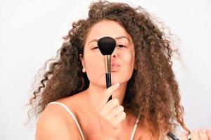 schöne junge lächelnde frau tragen make-up mit pinsel auf. isoliert foto